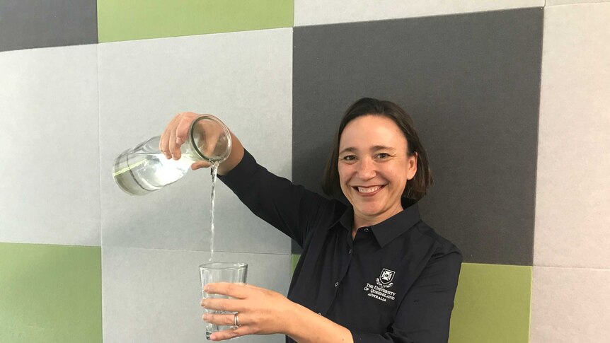 Professor Sara Dolnicar pours water from a jug into a glass.