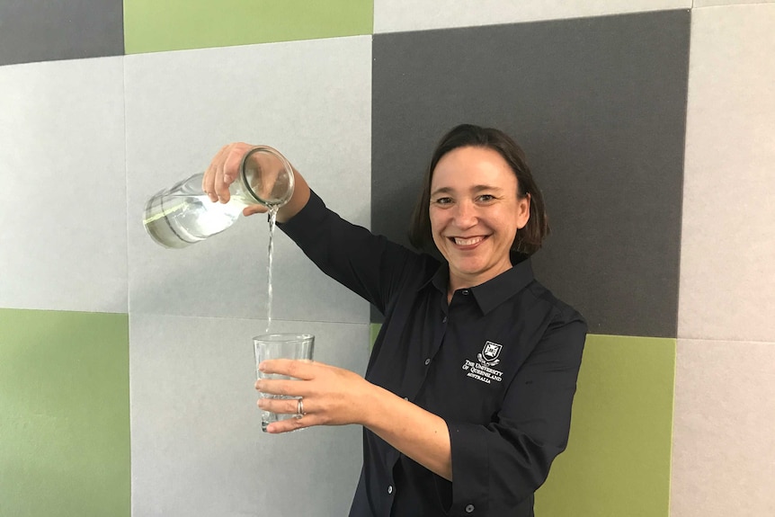 Professor Sara Dolnicar pours water from a jug into a glass.