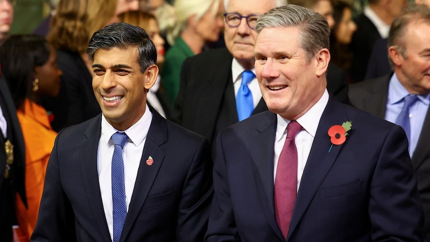 A man in a suit wearing a blue tie standing next to a man in a suit with a red tie.