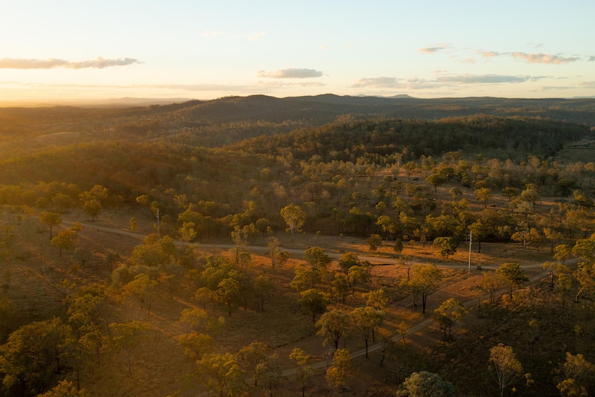 An aerial shot of the sun setting behind a vast open plain.