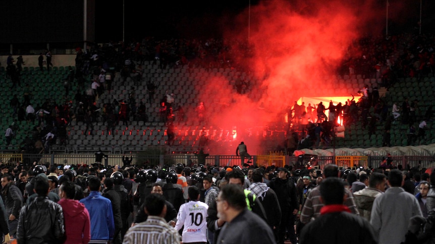 Soccer fans flee from a fire during a riot that erupted after a match between Al-Ahly and Al-Masry.