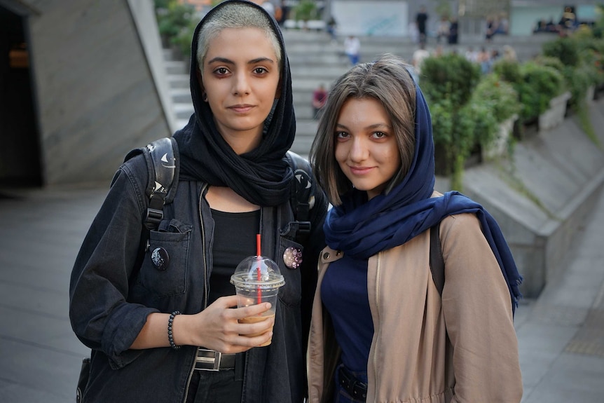 Two women, wearing hijabs partially covering their hair, pose for the camera.