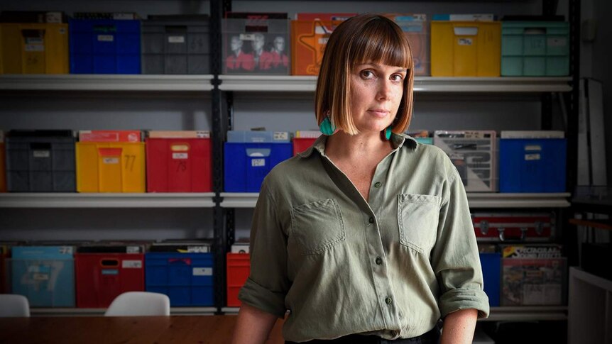 Adelle Robinson Director of Fuzzy music sits inside her Sydney office surrounded by plastic boxes full off records.