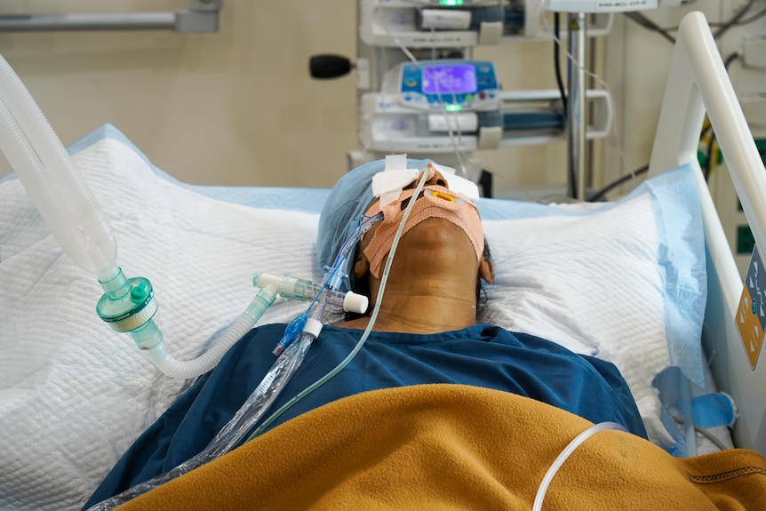 A woman in a hospital bed attached to a ventilator