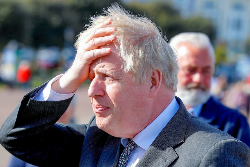Boris Johnson pushing back his blonde hair while looking off into the distance 