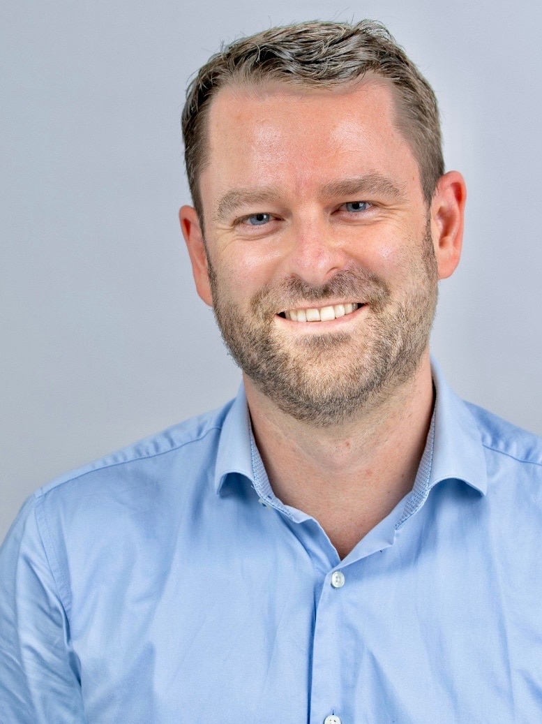 Man with blue eyes smiles at camera in professional photograph