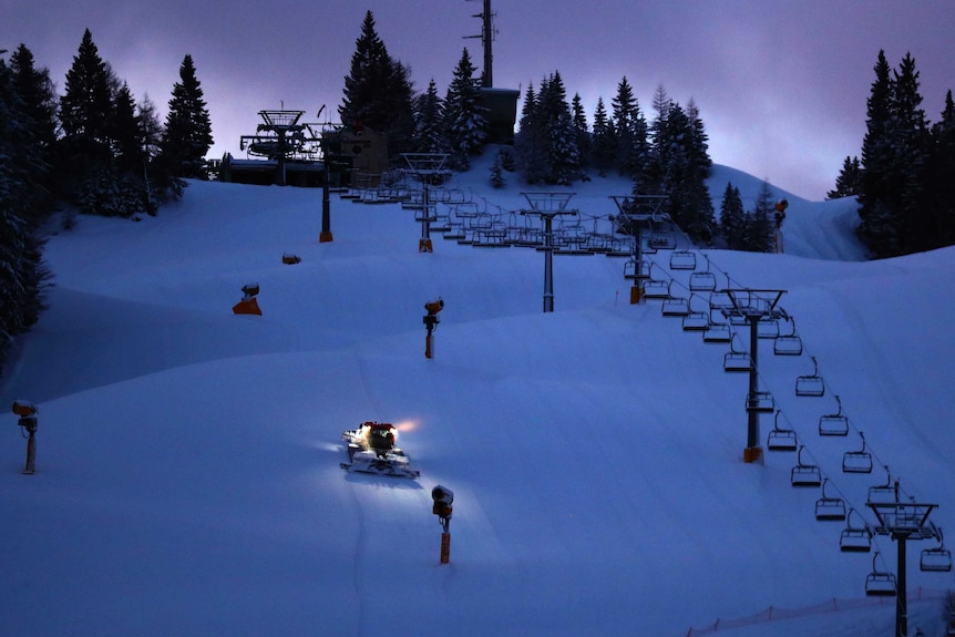 A snowcat smooths the grade on the ski slope in the early morning in the Austrian province of Tyrol, in Seefeld.