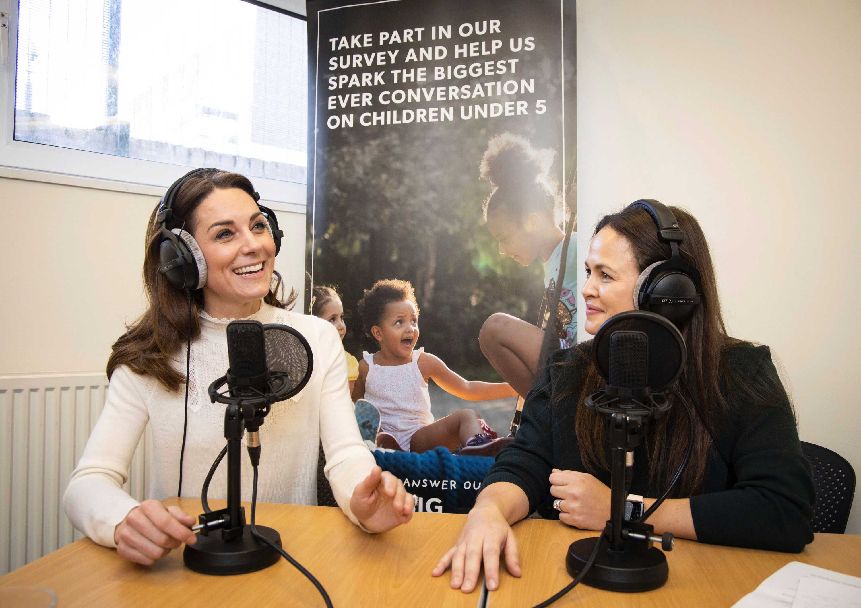 Two women sitting in a recording studio with headphones on talking and smiling