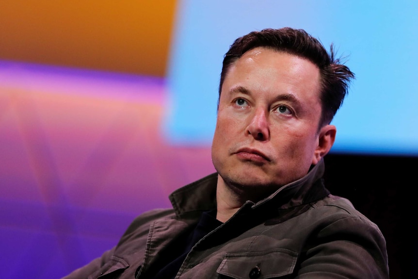 A close up of Elon Musk's face. He is unsmiling and appears to be concentrating on a person off-camera.
