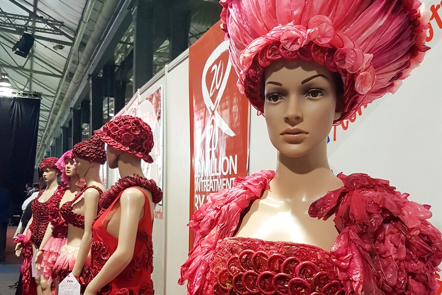 Mannequins are dressed in clothes decorated entirely in red condoms.