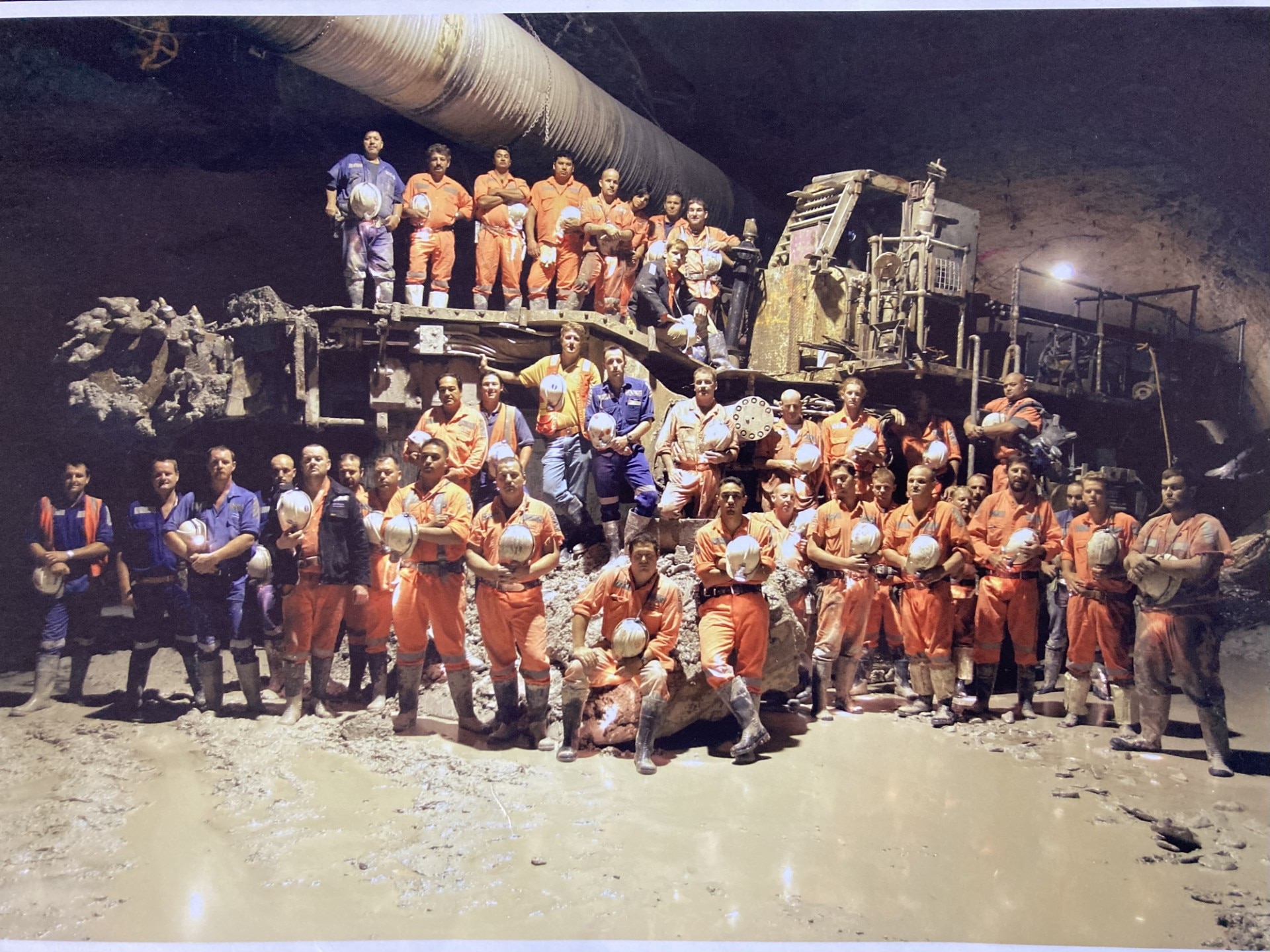 A group of workers in an underground tunnel with a large piece of machinery