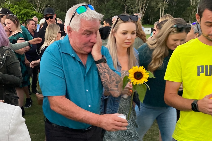 An emotional Reg Wilkinson rubs his eye as he walks through a crowd.