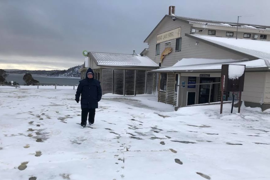 Person walking in snow near hotel.