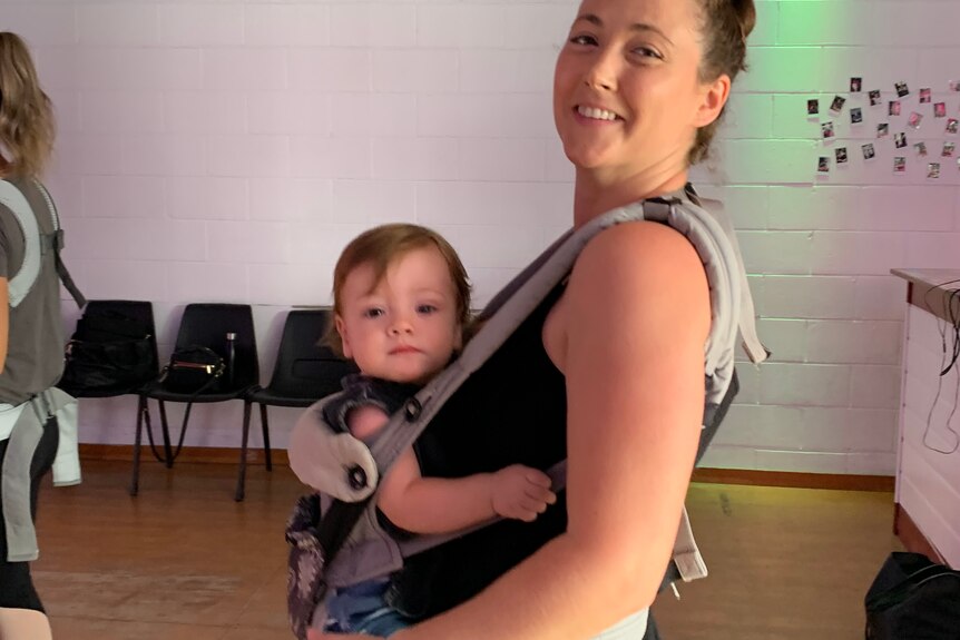 Young Mum with 11 month old baby in a pouch taking part in baby friendly dance class