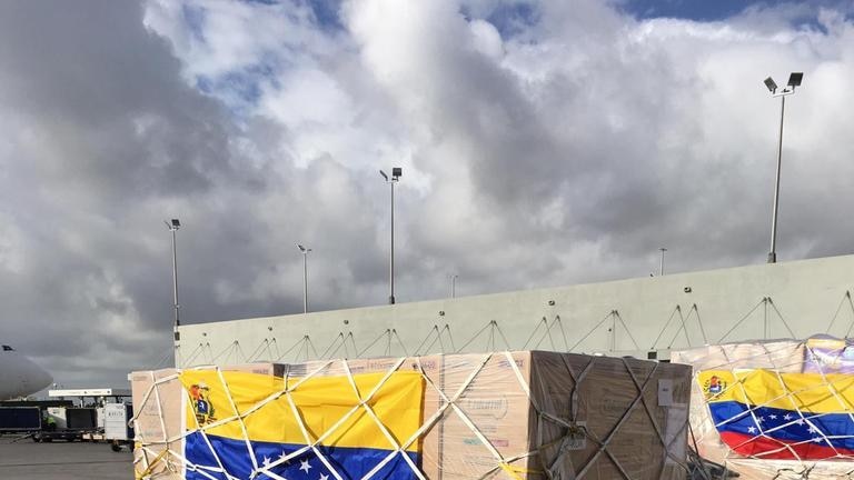 Wooden cartons of aid goods wrapped in the Venezuelan flag waiting to be loaded into planes