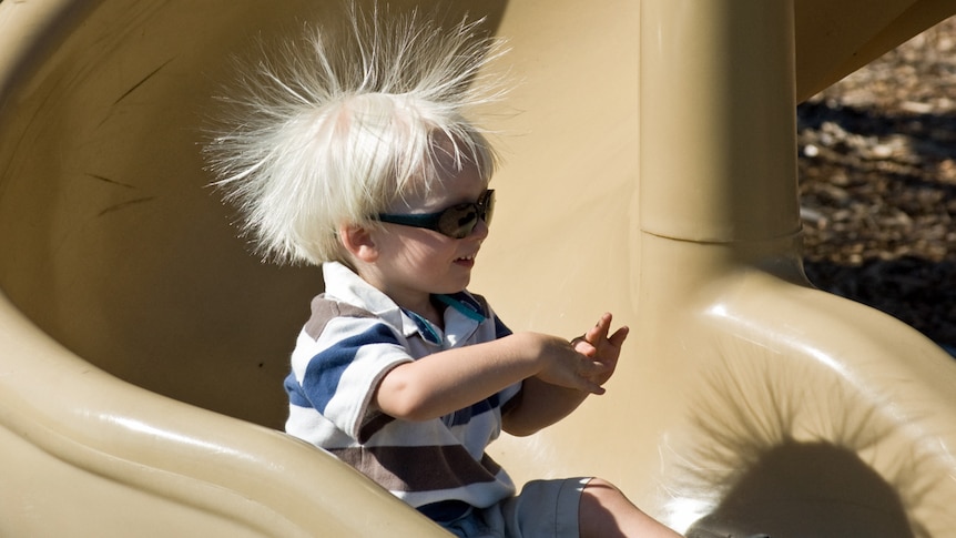 Young child on a slippery slide with static in his hair.