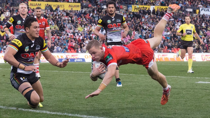 Matthew Dufty of the Dragons beats Panthers tacklers to score a try at Penrith Stadium.