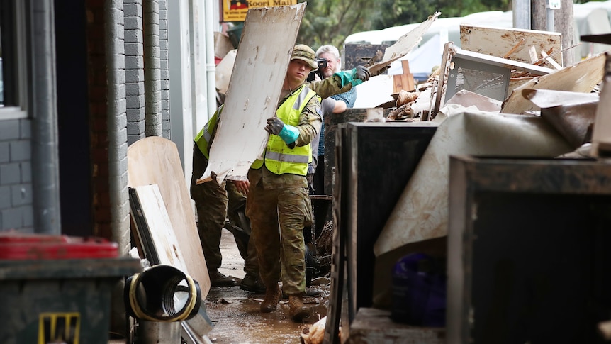Defence force personnel carrying debris in Lismore