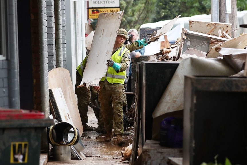 Defence force personnel carrying debris in Lismore