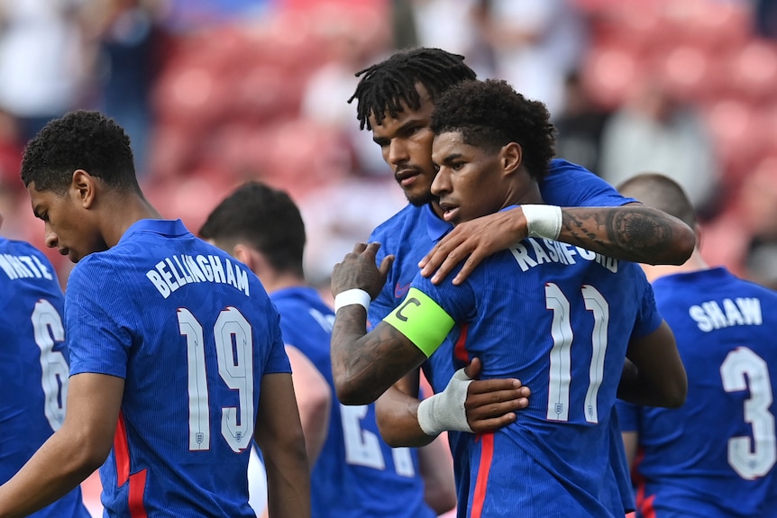 Marcus rashford celebrates by hugging teammates