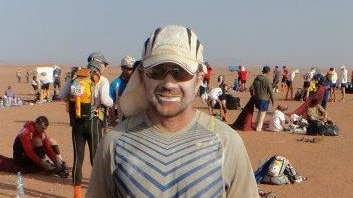 A man wearing a hat standing in the desert.