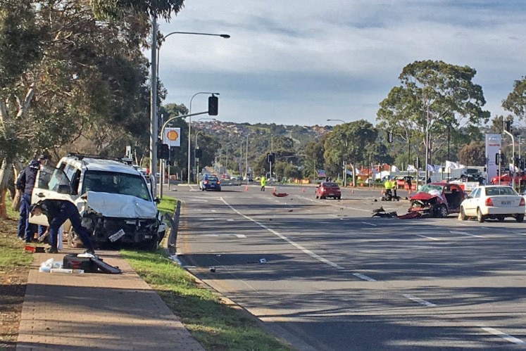 A crashed vehicle on the footpath and others across the roadway.