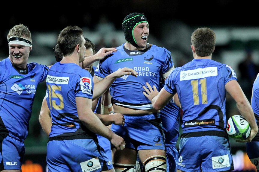 A smiling Adam Coleman of the Western Force is congratulated by his teammates after scoring a try.