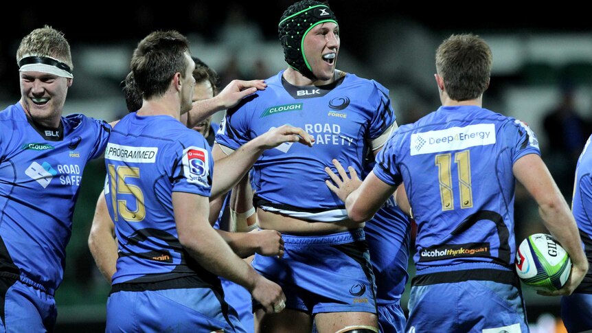 A smiling Adam Coleman of the Western Force is congratulated by his teammates after scoring a try.