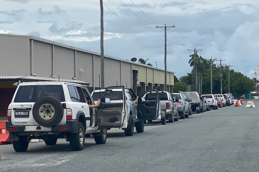 Cars lined up outside a COVID-19 testing clinic at the Mackay Showgrounds. Some people have their feet up on their car doors.