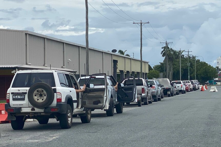 Cars line up down a street, sone with their doors open