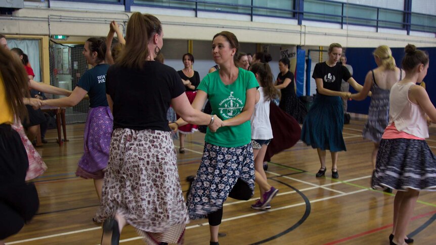 A group of women pair up to practice a Hungarian folk dance