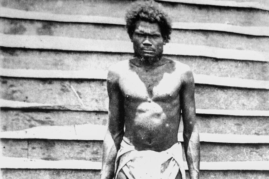 Historical photo in black and while of an islander worker, shirtless and in a loin cloth.