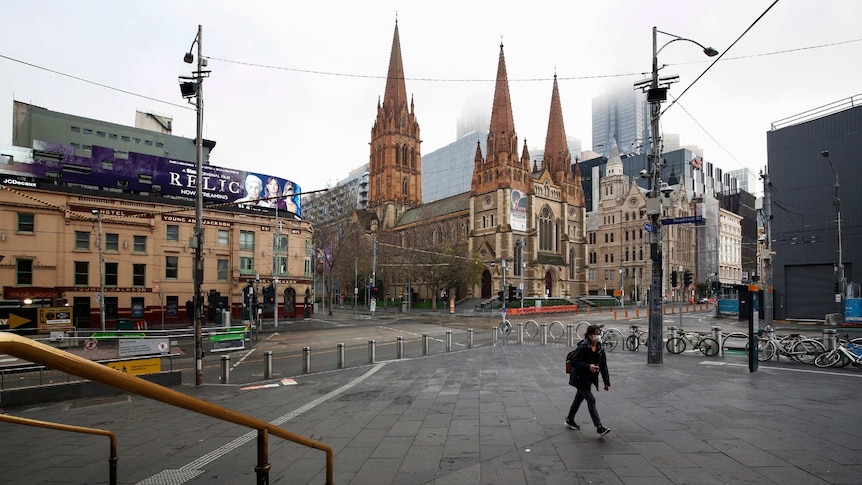 A man crosses walks along an empty street near Flinders Street Station.