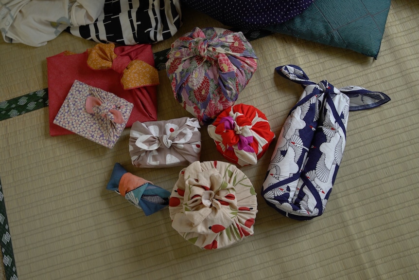 eight different sized gifts wrapped in colourful, bright fabrics laid out on the floor