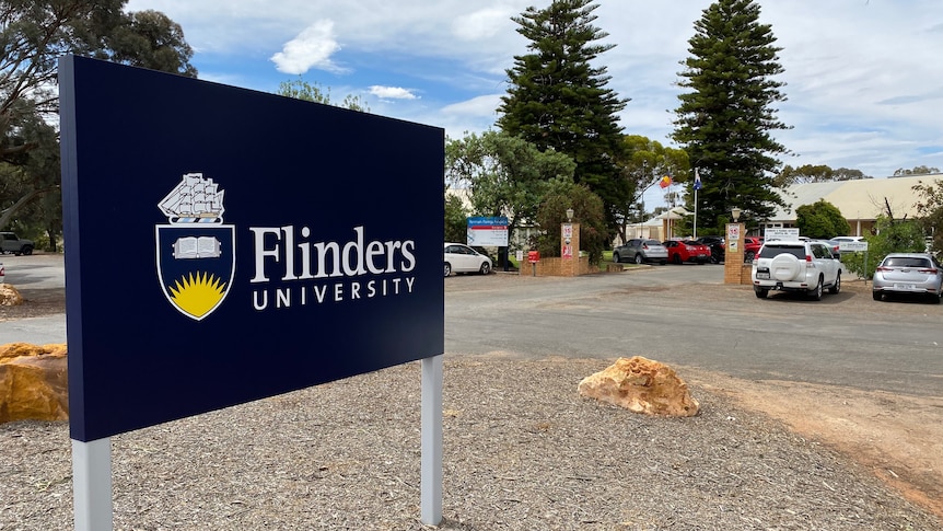 A blue sign out the front of a building that says "Flinders University".
