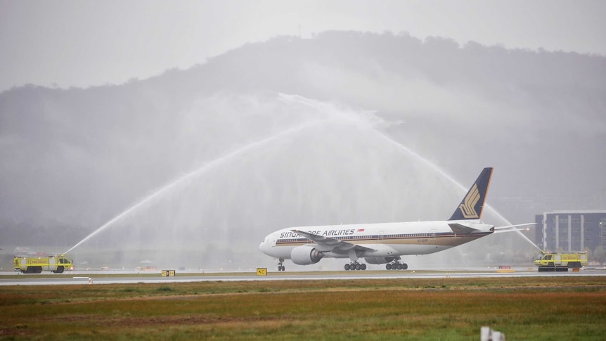 A plane touches down under two water spouts.