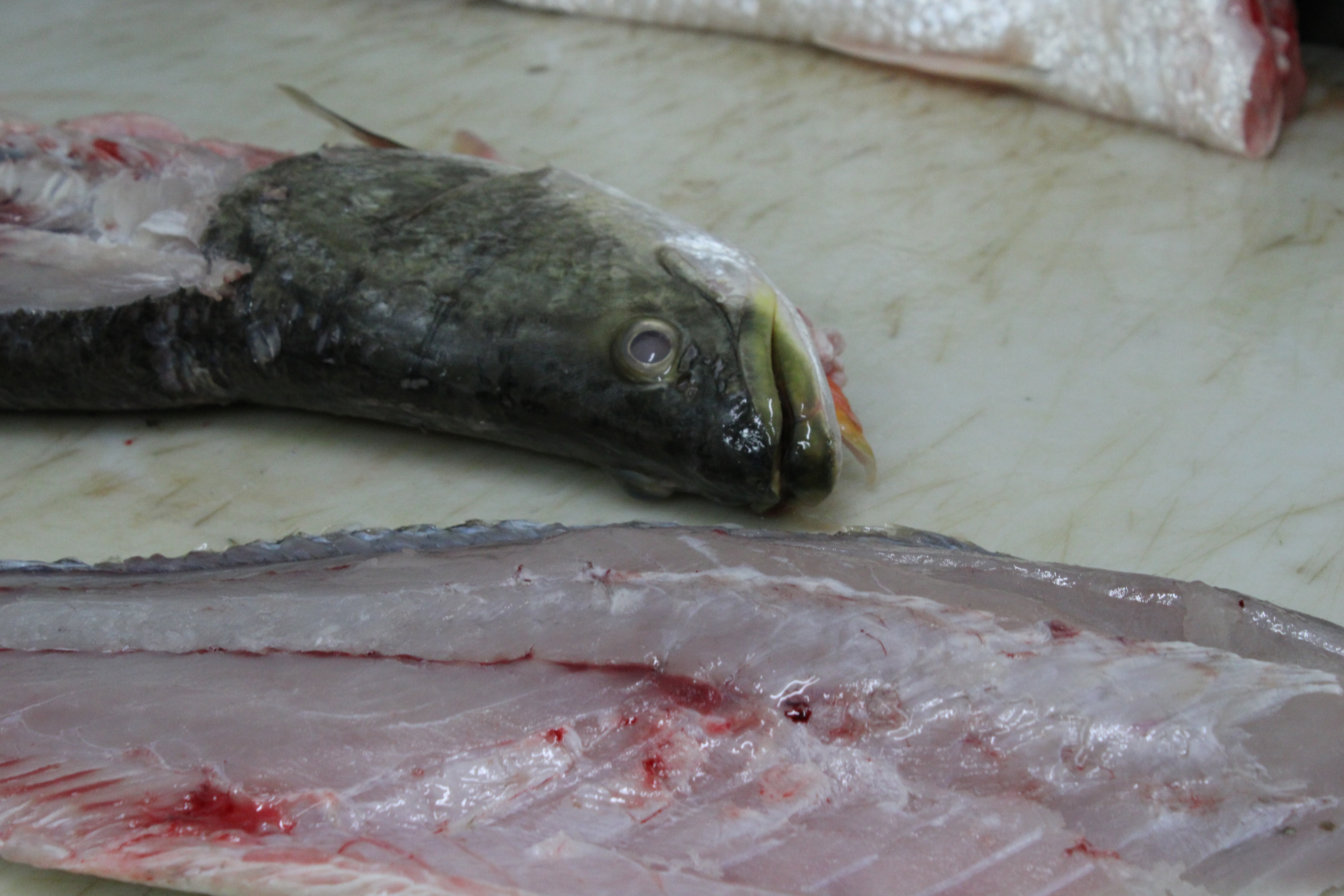 Un barramundi entero cortado por la mitad mostrando su carne.