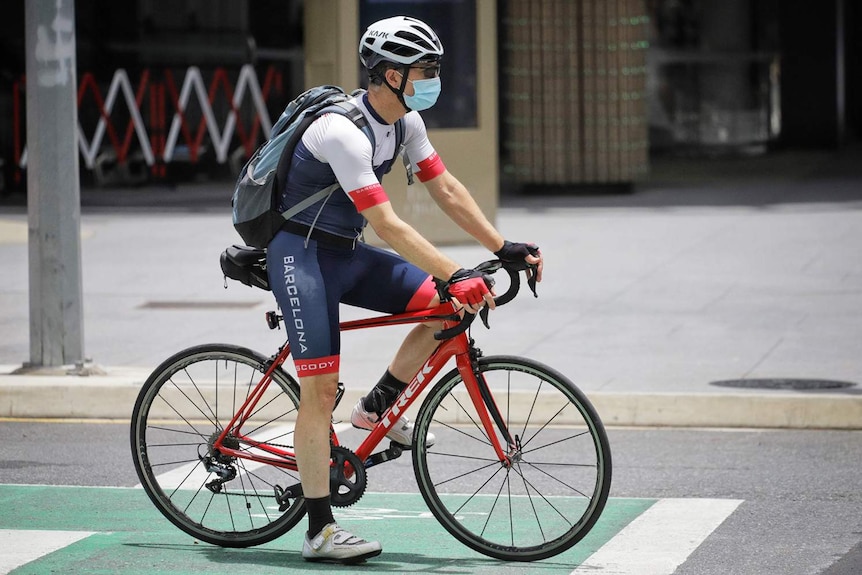 Cyclist wearing a mask rides his bike in Brisbane's city on January 11, 2021.