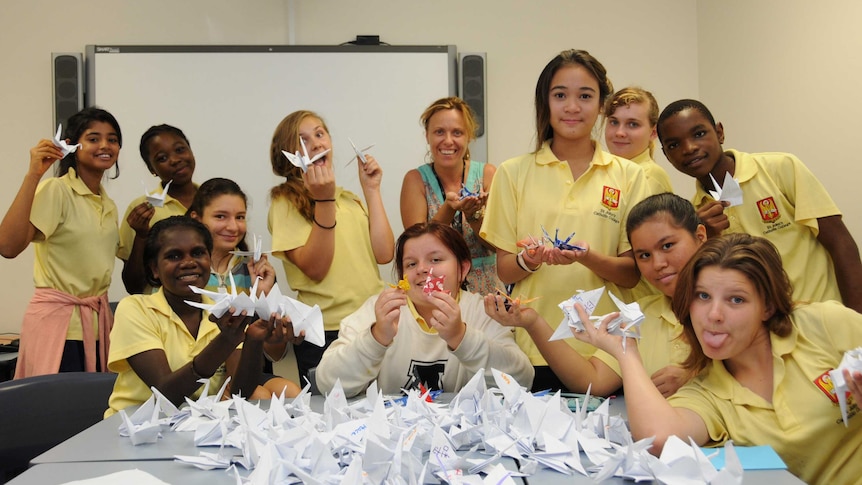 A group of high school students hold paper cranes.