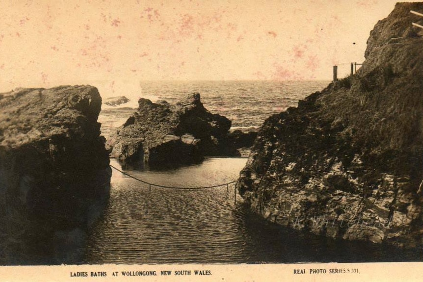 Sepia-coloured postcard shows calm pool water between rocky cliffs. A single chain across the pool links the cliffs.