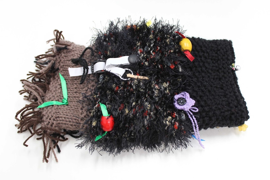 A knitted Twiddle Muff with various embellishments on it.