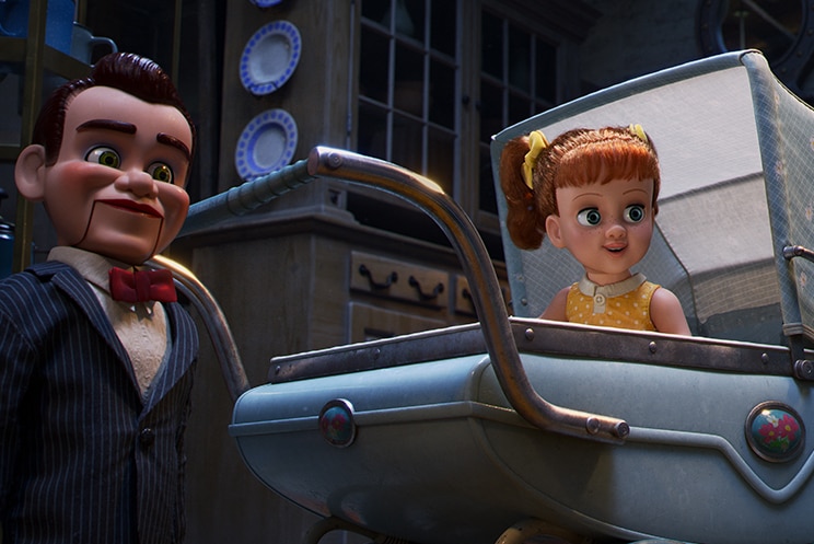 Colour still of toys Benson, standing next to Gabby Gabby, sitting in pram, both looking at Woody in animated film Toy Story 4.