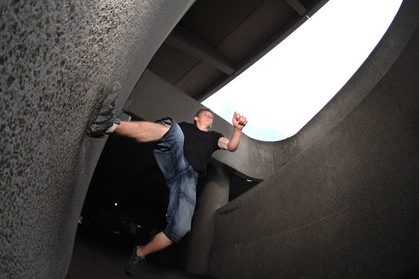 A man lunges for a retaining wall as he executes the Parkour move the "Tic-Tac" in inner Melbourne.