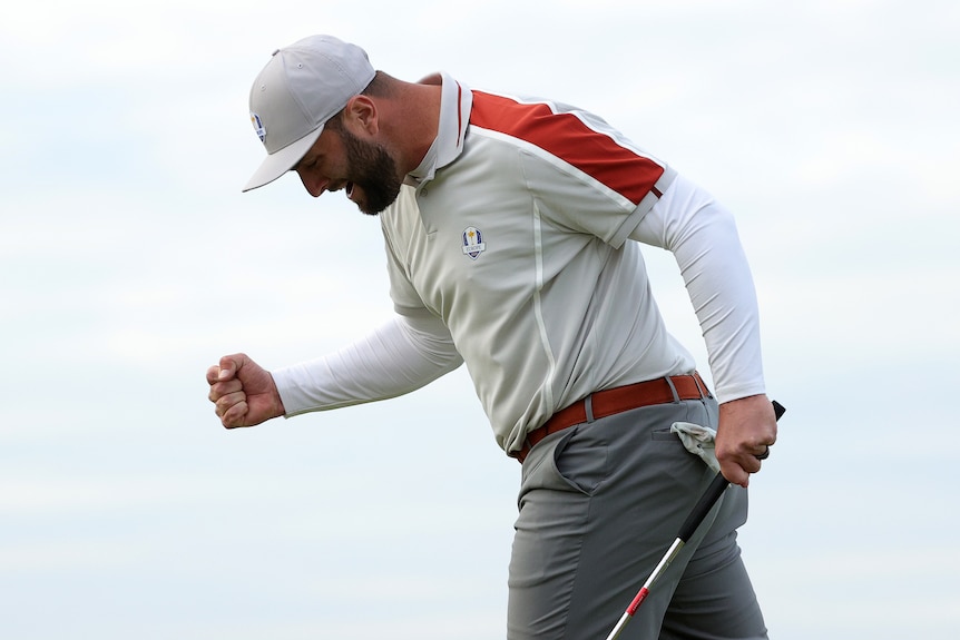 Jon Rahm clenches his fist and bends at the waist