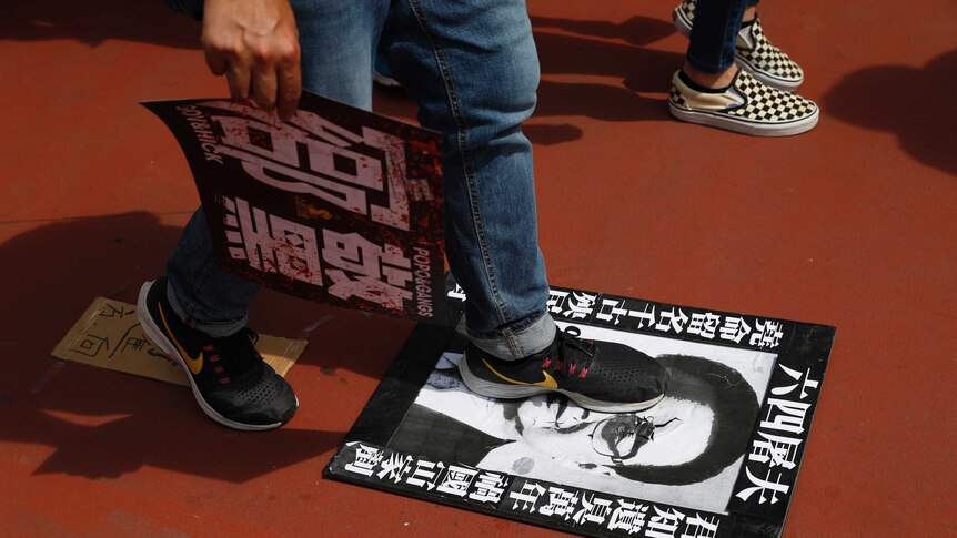A protester steps on a poster depicting former Chinese Premier Li Peng reading "June 4th Butcher"