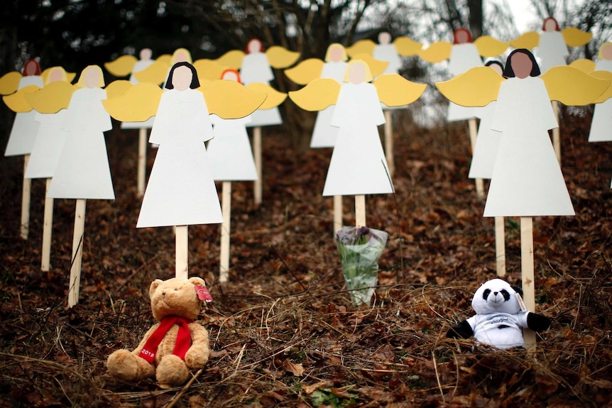 Stuffed animals sit beneath wooden angels near the Sandy Hook Elementary School.