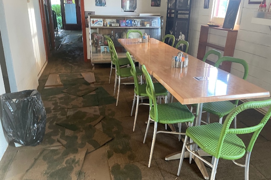 A photo showing flood damage to Coffee shop. Green chairs and table shown, which mud prints on the floor.