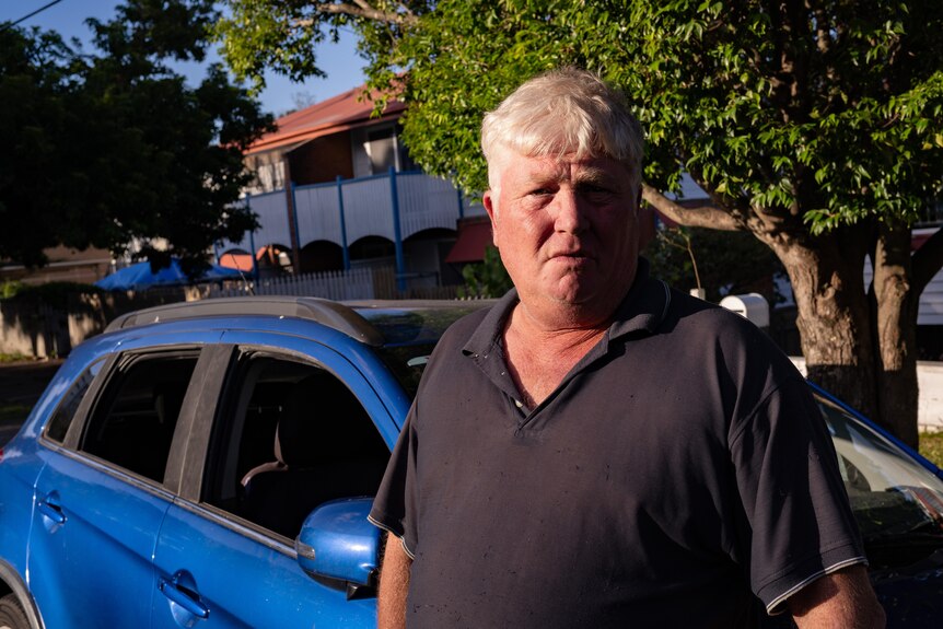 A man next to a car with smashed windows