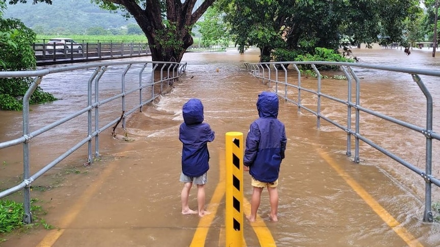 Two boys stand near a flooded park