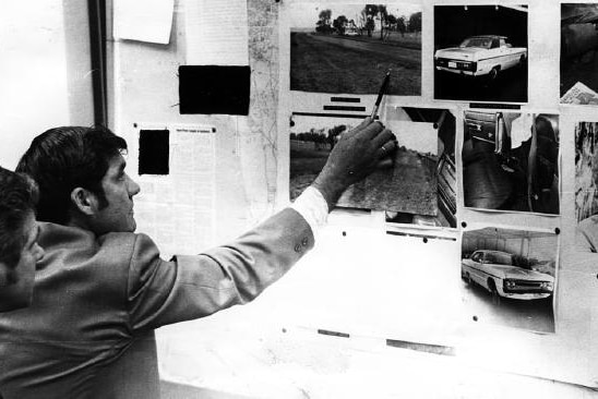 Detectives looking of photos of the crime scene of the 1975 murder of Perth brothel madam Shirley .